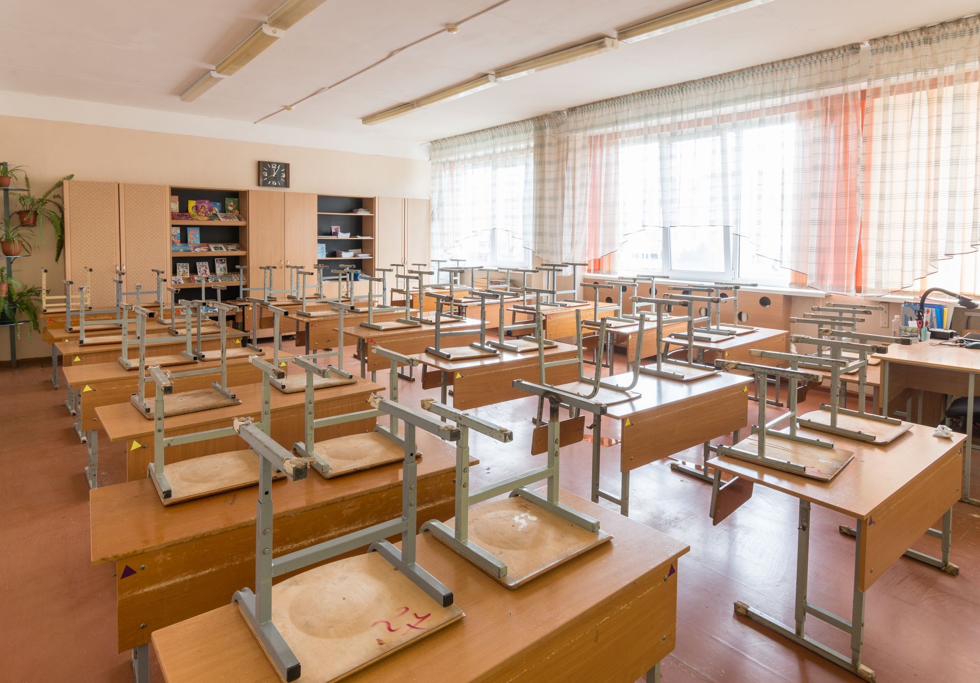 A classroom with tables and chairs without students in it.