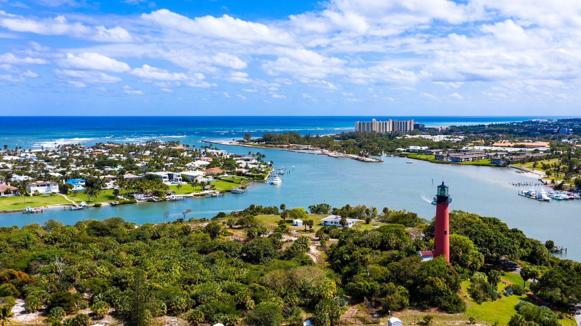 An aerial view of a lighthouse on a small island in the middle of a body of water.