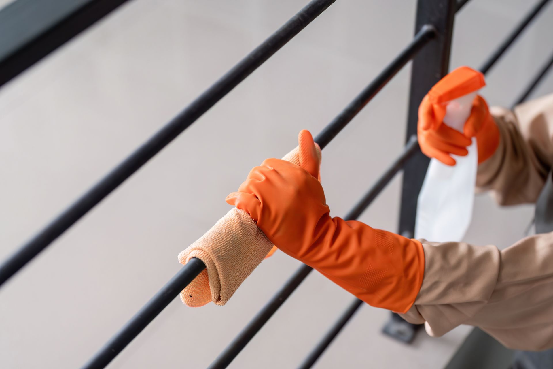 Cleaning a railing with a cloth and spray bottle.