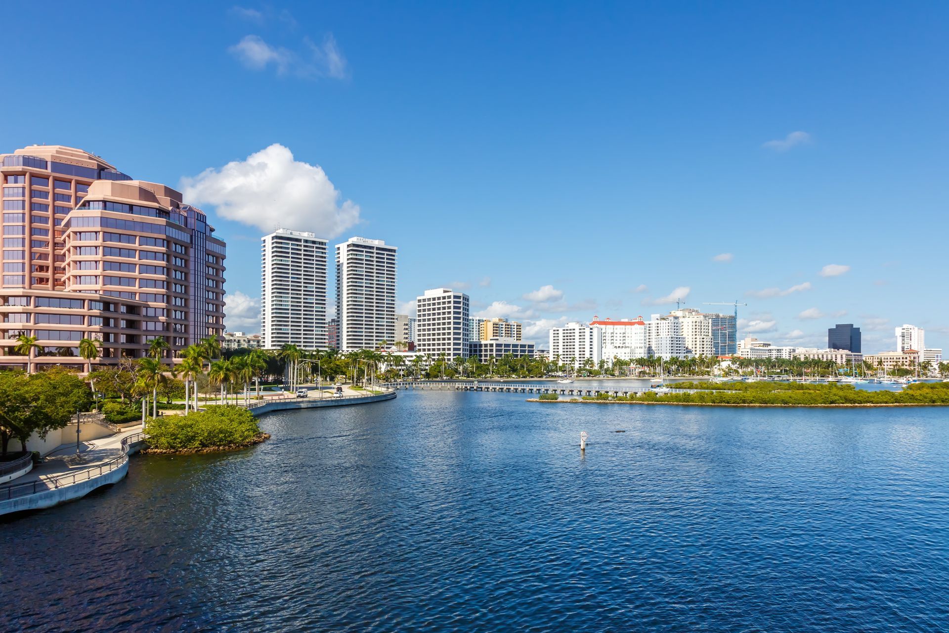 A city skyline with a lake in the foreground and buildings in the background.
